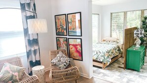 Ein Zimmer mit einem Bett, einem Sessel, einem grünen Schrank und einer Wand mit gerahmten Bildern.