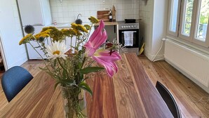 Een moderne keuken met een houten eettafel, een bloevas en een witte koelkast.
