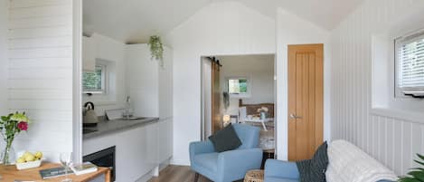 A compact living space with a kitchenette, a blue sofa, and a dining area.