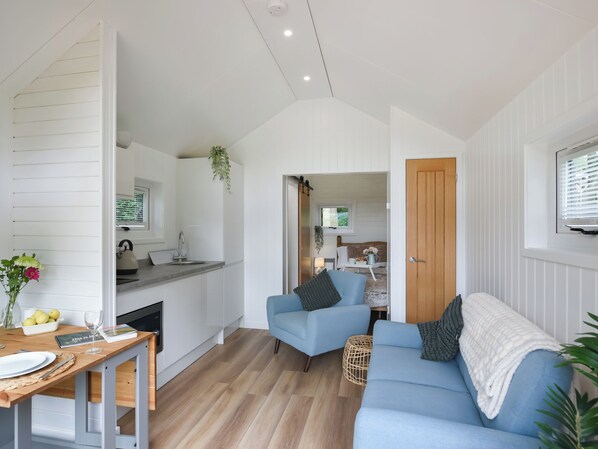 A compact living space with a kitchenette, a blue sofa, and a dining area.