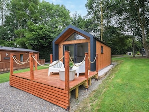 A small wooden cabin with a deck and a single chair.