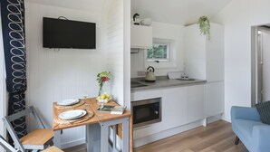 Una cocina compacta con horno empotrado, lavamanos y ventana con persianas.