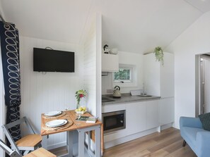 Une cuisine compacte équipée d’un four encastré, d’un évier et d’une fenêtre avec des stores.