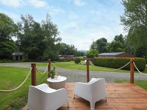 A wooden deck with two white chairs and a round table with a bottle and glasses. - Mini Lodge - UK47682 (Montgomery)