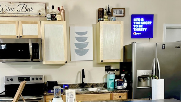 A kitchen with a bar area, including a microwave, stove, refrigerator, and bar stools. - Fun 2 BdRm Apt in the Bourbon Capital with Pool Table, PAC-Man & More! (Bardstown)