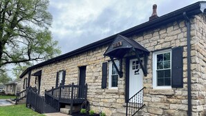 A stone building with a black roof, a white door, and a black staircase leading to the entrance. - Fun 2 BdRm Apt in the Bourbon Capital with Pool Table, PAC-Man & More! (Bardstown)