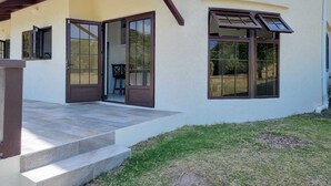 A modern house with a covered porch, a stone staircase, and a grassy yard. - The Swallow Nest 1 (Gros Islet)