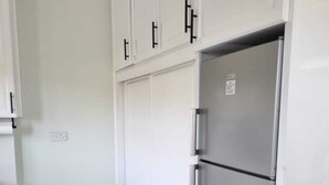 A kitchen with white cabinets, a stainless steel refrigerator, and a white trash bin. - The Swallow Nest 1 (Gros Islet)