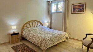 A bedroom with a bed, bedside lamps, a chair, a rug, and a window with curtains.