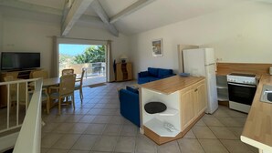 A spacious living area with a TV, seating, and a kitchen with a stove and refrigerator.