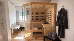 Un cuarto de sauna con bancos de madera, un panel de vidrio y un perchero para toallas.