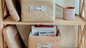 Ein Holzregal mit gewebten Körben, Büchern und gerahmten Schildern.