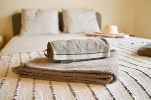 A neatly made bed with a striped bedspread and a folded towel.