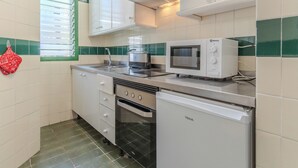 Ett kompakt kök med vita skåp, en mikrovågsugn, en brödrost och en diskmaskin.