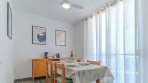 En matplats med ett bord dukat för fyra personer, trästolar, en kaffebryggare och två inramade konstverk på väggen.