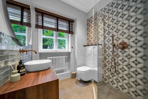 Un baño moderno con un ventanal grande, un lavamanos blanco, un inodoro y una zona de ducha.