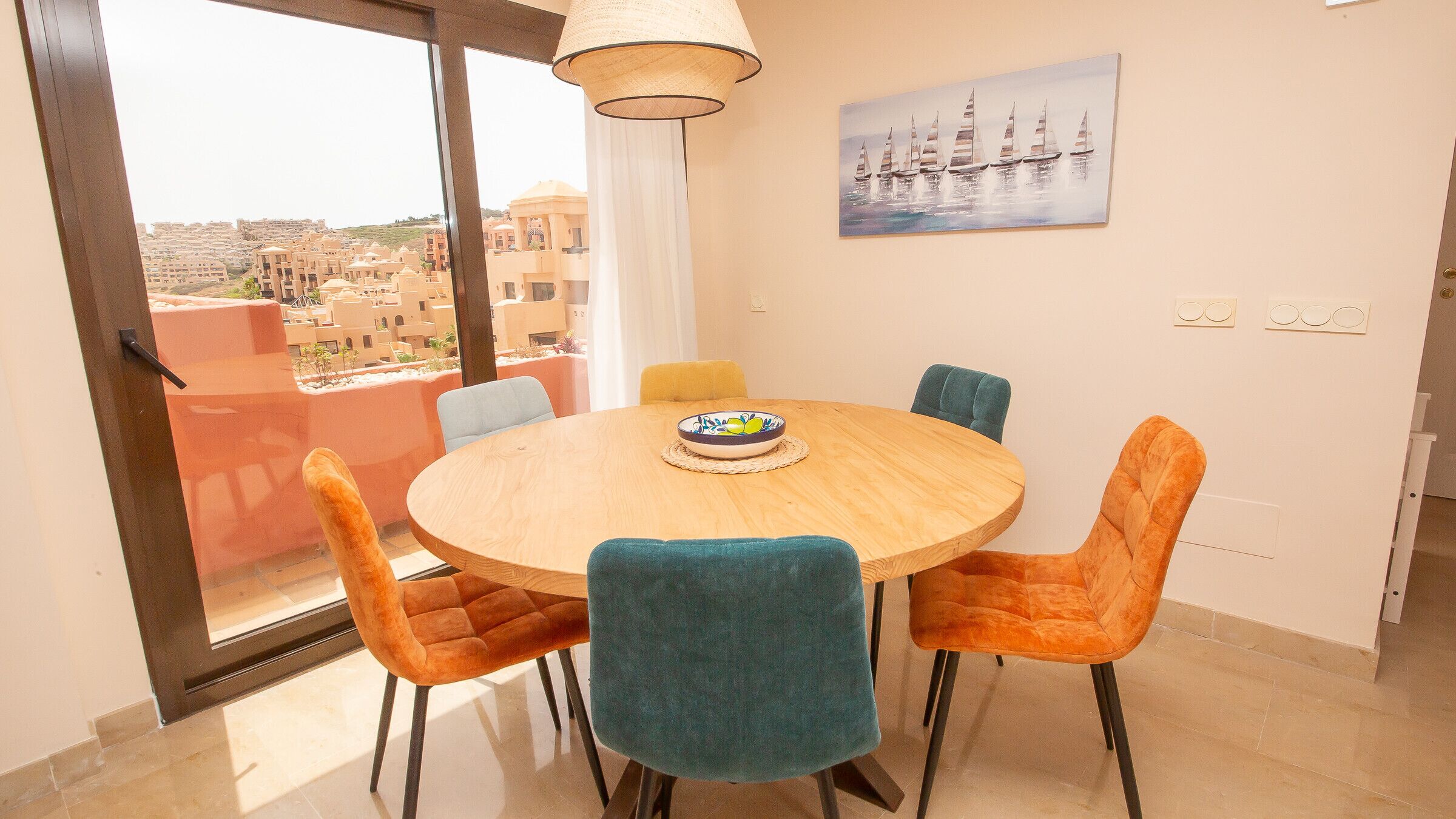Un comedor con una mesa redonda, cuatro sillas y un cuenco de fruta.