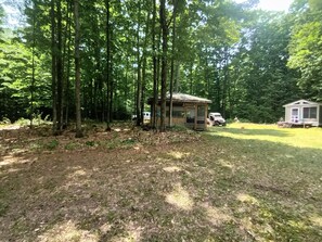 Une cabane située dans une zone boisée, accessible par un sentier de terre.