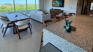 A modern living room with a dining area, a sofa set, a coffee table, and a TV mounted on the wall. - Luxury Retreat, VGolf. Marina Vallarta. (Puerto Vallarta)