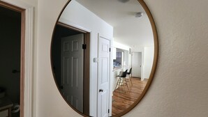 Un couloir avec une porte blanche, un coin cuisine avec un comptoir et des chaises, et un plancher en bois.