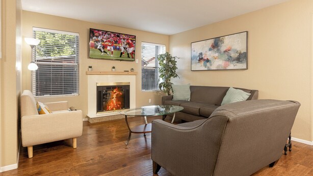 A living room with a fireplace, a sofa, a glass coffee table, and a painting on the wall. - Adventurers Base Camp! (Boise)