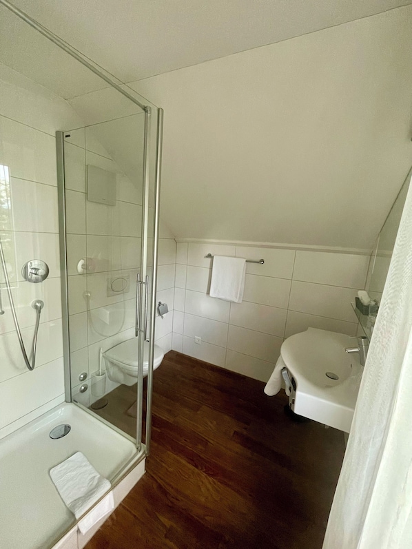 A bathroom with a glass shower enclosure, a toilet, a sink, and a bathtub. - Gasthof Rössli (Steinhausen)