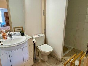 Ein Badezimmer mit Waschbecken, Spiegel, Toilette und Duschbereich.