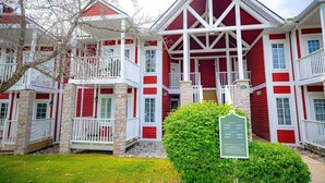 Een rood-wit huis met twee verdiepingen, een balkon en een bord met het huisnummer.