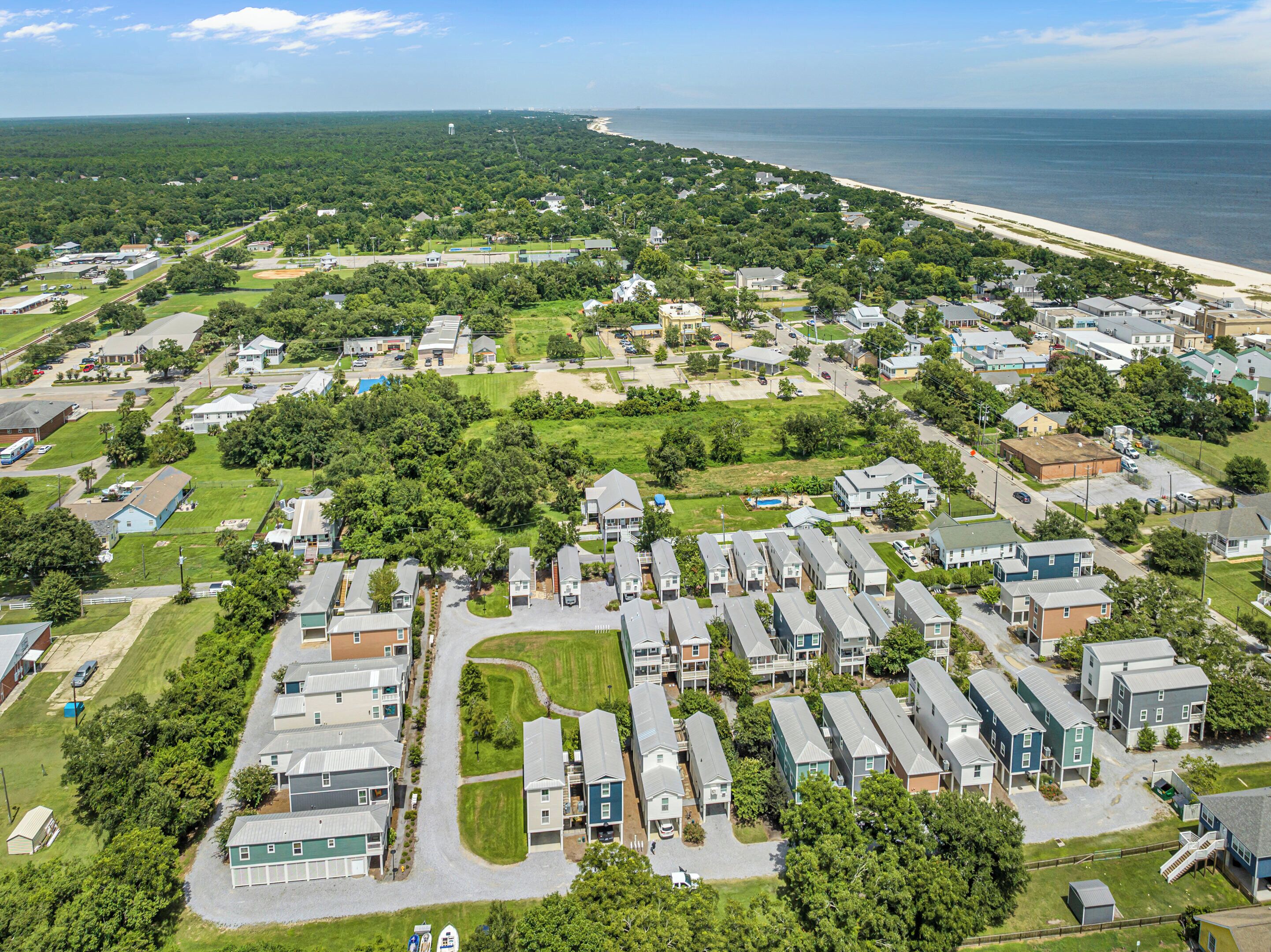 A residential area with detached houses, a beach, and a water tower in the distance.