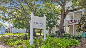 A sign for cottages at 2nd street, surrounded by lush greenery and a well-maintained garden.
