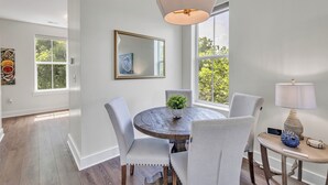 A dining area with a round wooden table, four chairs, a potted plant, and a lamp.