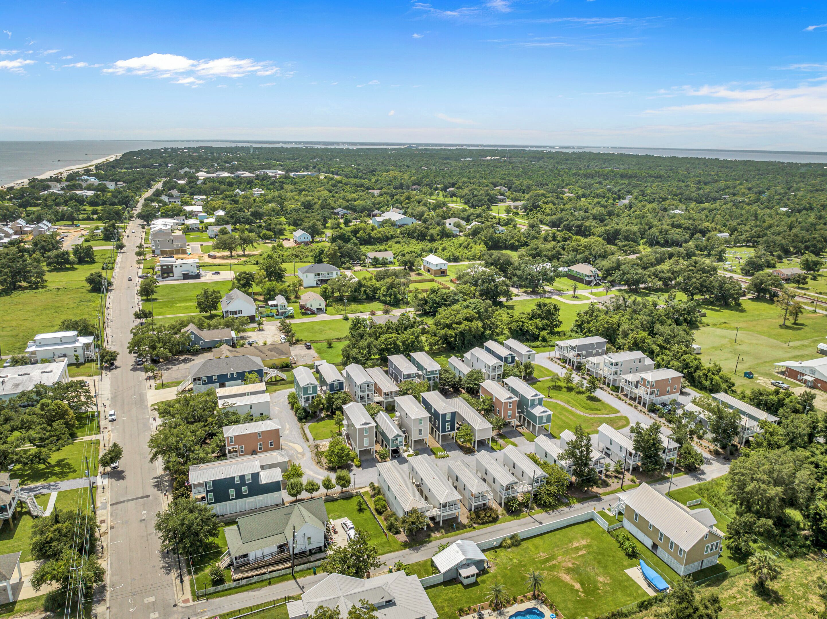 An aerial view of a residential area with houses, roads, and a beach in the background.