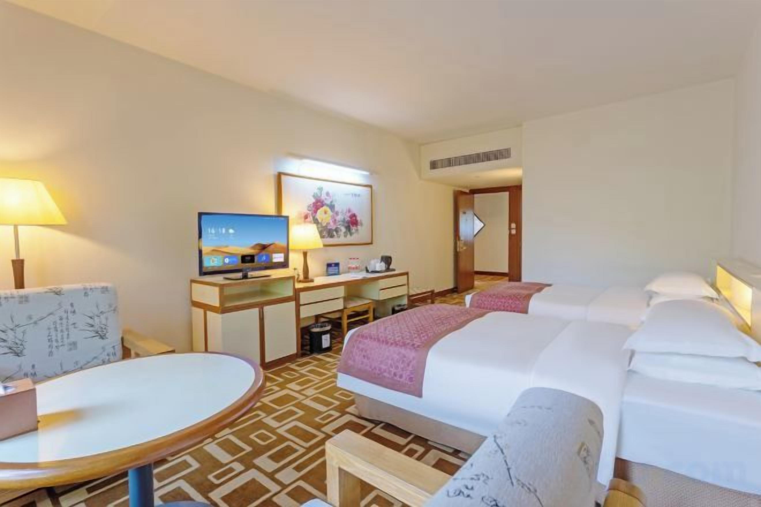Habitación de hotel con cama, escritorio con computadora, una silla y televisor.
