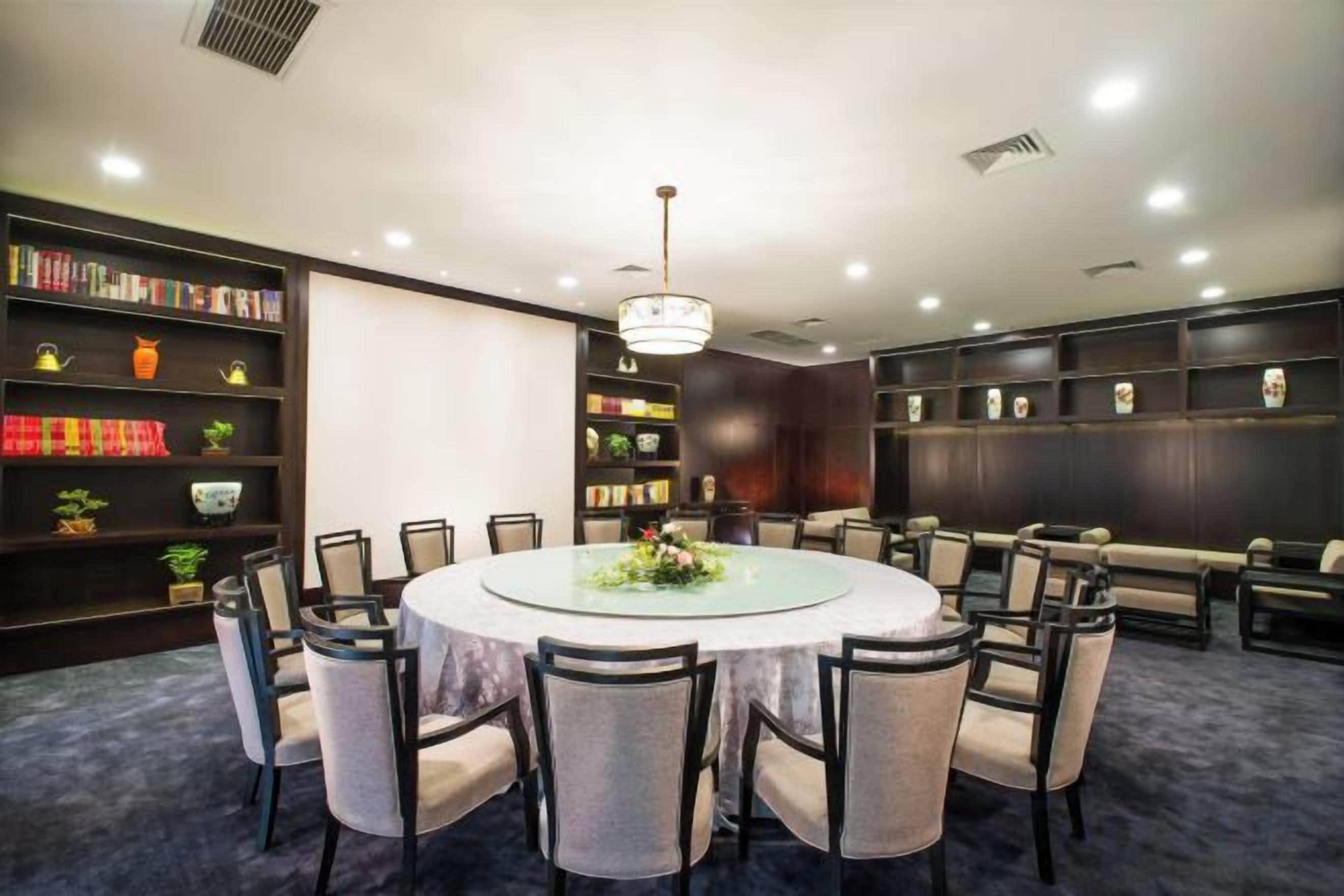 A conference room with a round table, chairs, and bookshelves.
