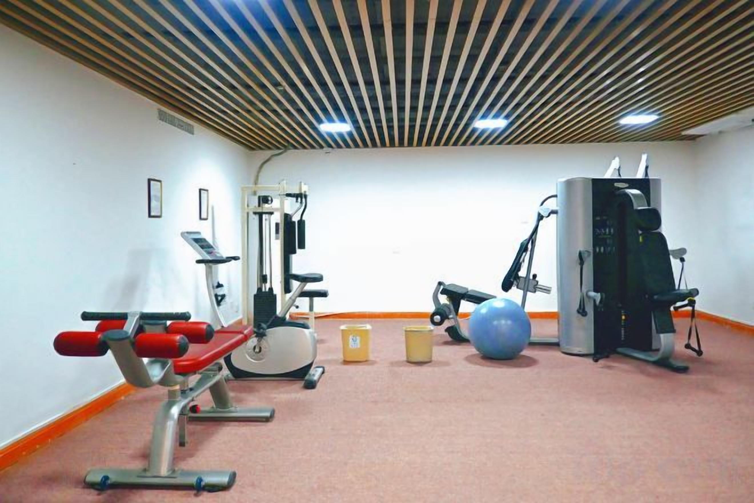 A gym with exercise equipment, a wall-mounted machine, and a large exercise ball.