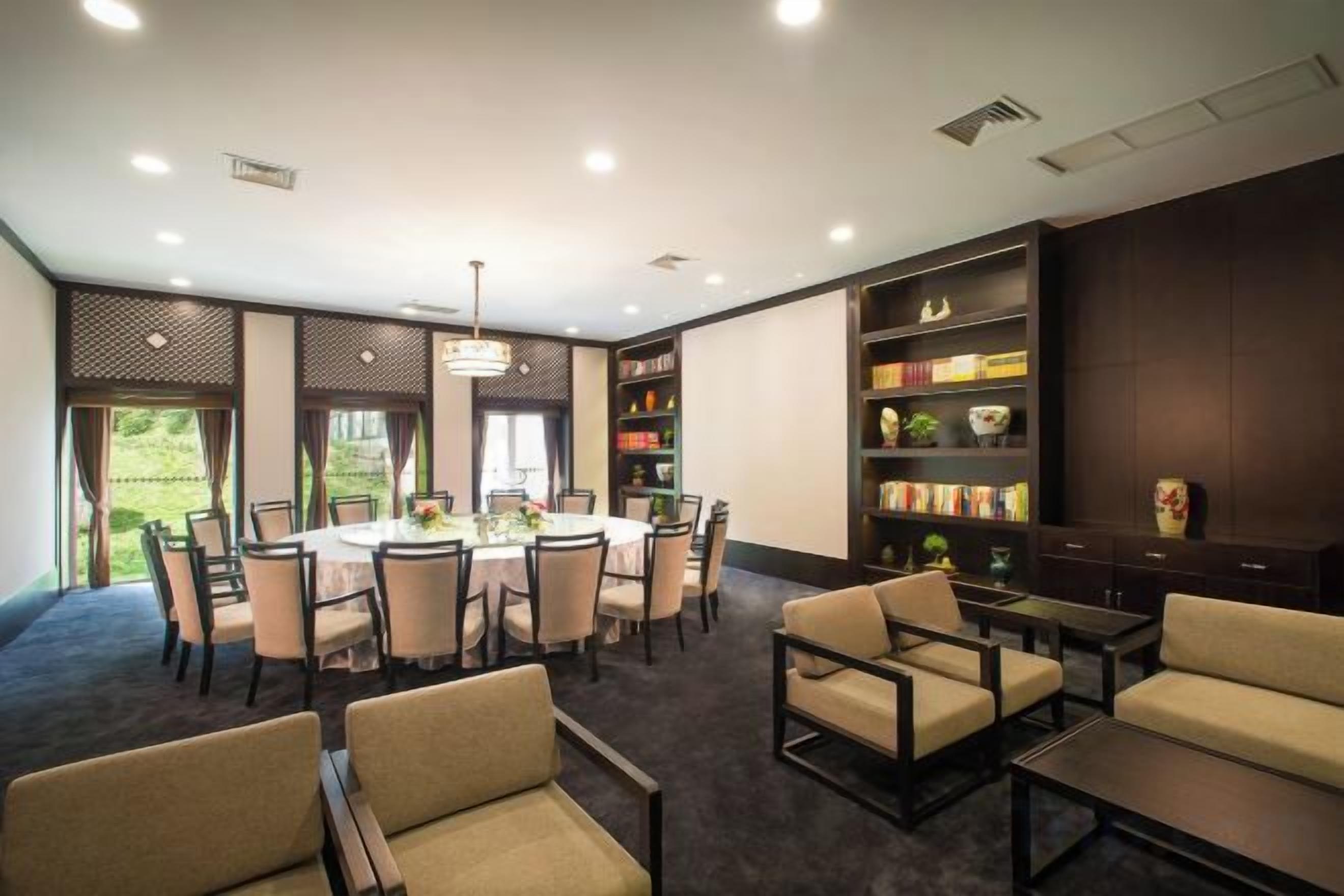 A conference room with a round table, chairs, and a bookshelf.