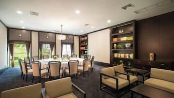 A conference room with a round table, chairs, and a bookshelf.
