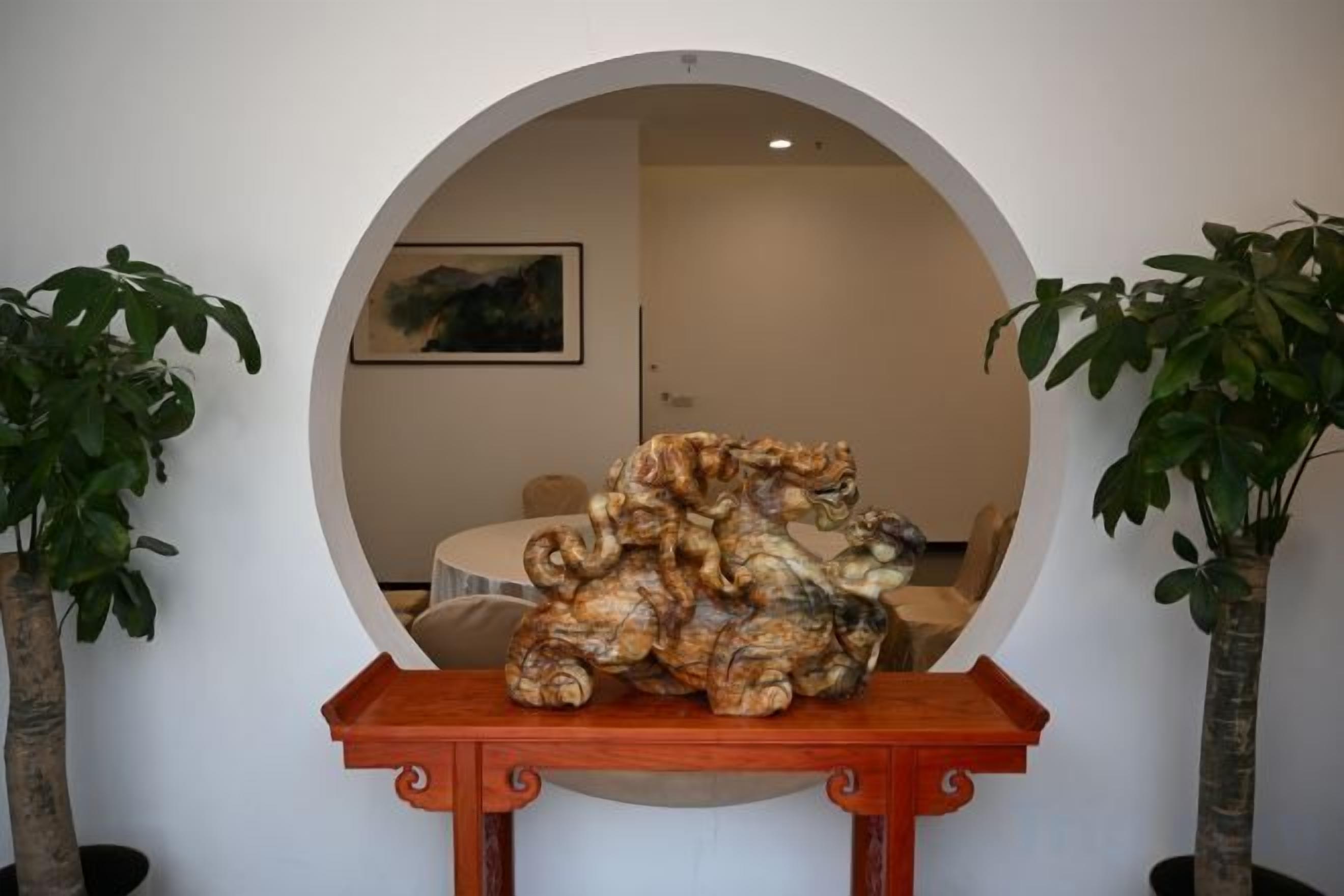 Espejo redondo que refleja una habitación con una mesa de madera y dos plantas en macetas.