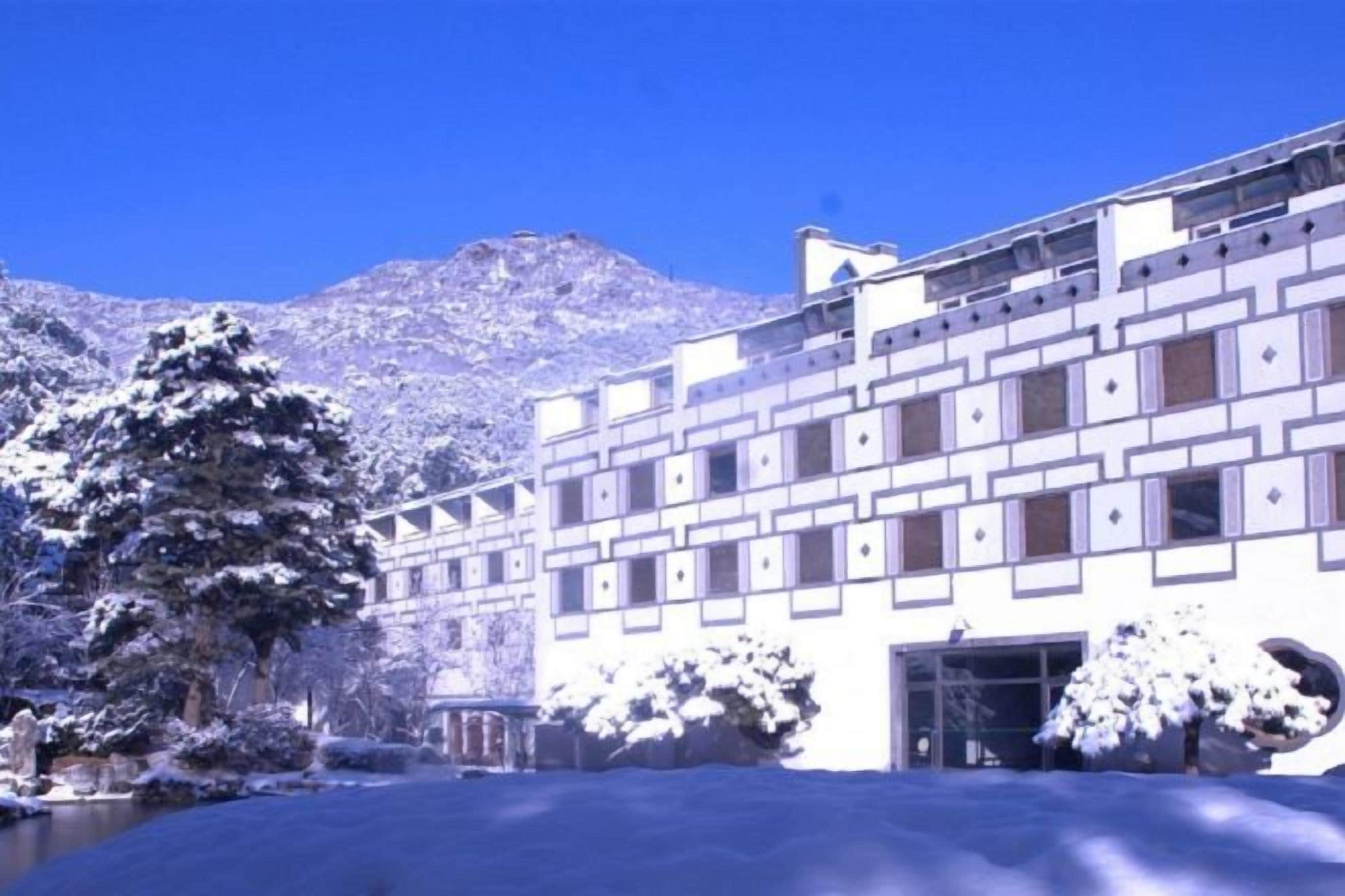 A building with a symmetrical facade, multiple windows, and a snow-covered landscape.