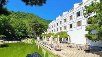 A hotel with a pool, outdoor seating, and a mountain backdrop.