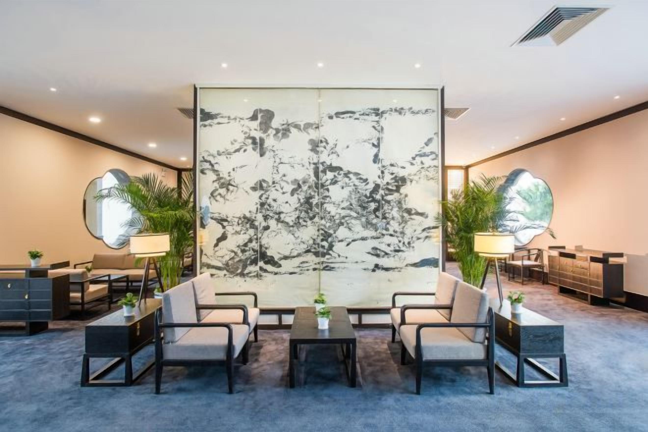 A modern hotel lobby with a large abstract painting, a reception desk, and seating arrangements.