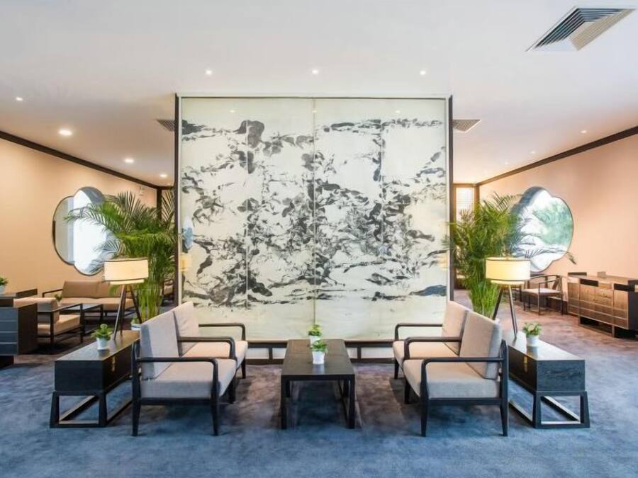 A modern hotel lobby with a large abstract painting, a reception desk, and seating arrangements.
