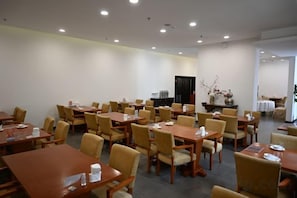 A conference room with multiple tables and chairs, a blackboard, and a decorative vase. - Fragrant Hill Hotel (Beijing)
