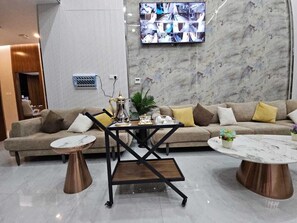 A modern living room with a sofa, two coffee tables, and a television mounted on the wall. - شقق أعمار الديار للشقق المخدومة  (Jeddah)