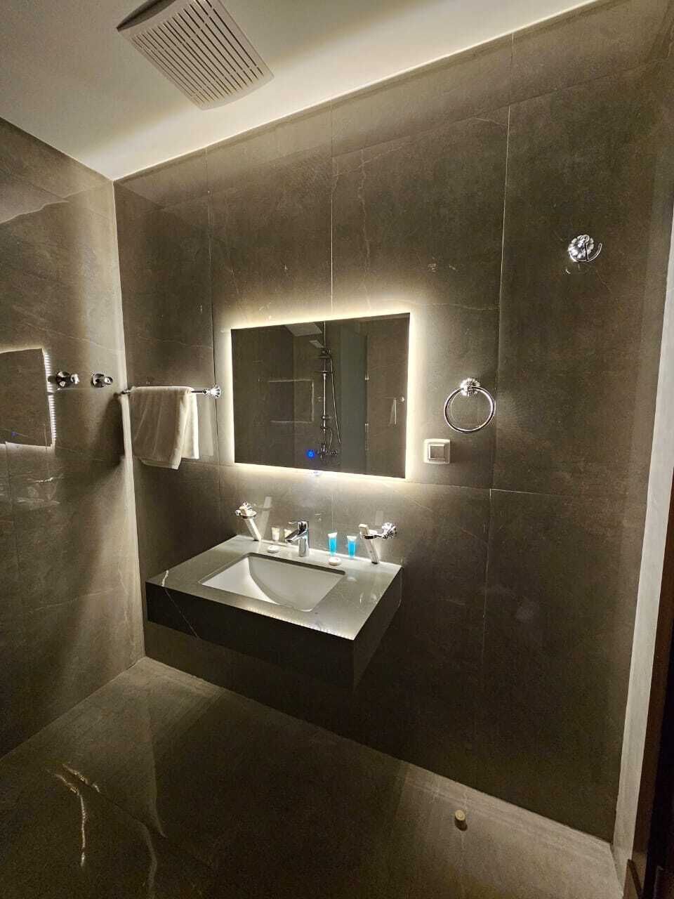 A modern bathroom with a large mirror, a sink, and a shower.