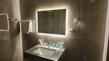 A modern bathroom with a large mirror, a sink, and a shower.