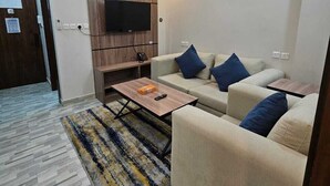 A modern living room with a flat-screen TV, a sofa set, a coffee table, and a patterned rug. - شقق أعمار الديار للشقق المخدومة  (Jeddah)