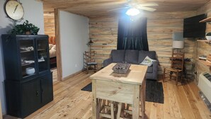 Un salon chaleureux avec un plancher en bois, un ventilateur de plafond, un canapé, une table basse, un meuble et un téléviseur.