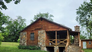 Une cabane en bois rustique, avec des fondations en pierre, une véranda et une cheminée.