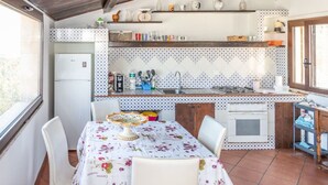 Una cucina compatta con zona pranzo, caratterizzata da piastrelle a parete, un frigorifero, un lavello e un piano cottura.